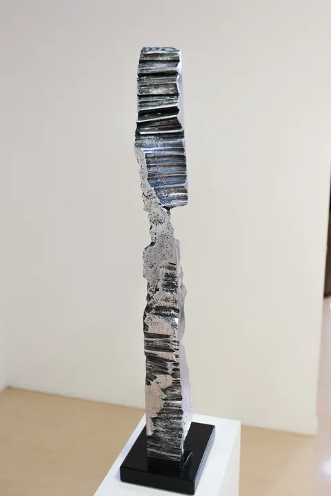 A polished aluminium column with a ridged surface on a black base