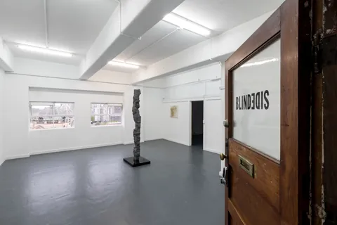 The gallery seen through its open timber door, the column standing in the middle of the room