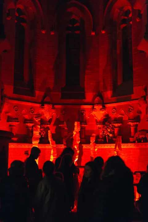Visitors in silhouette in front of the red-lit installation