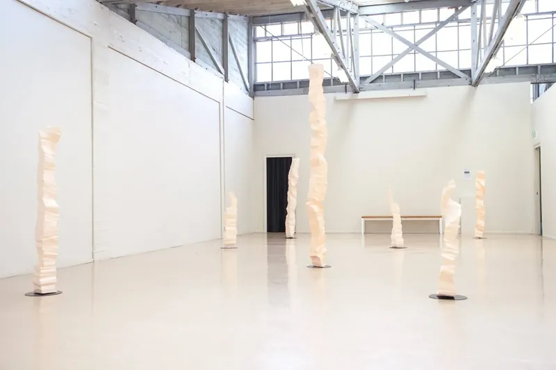 White polystyrene columns of varying heights spread through a large white gallery