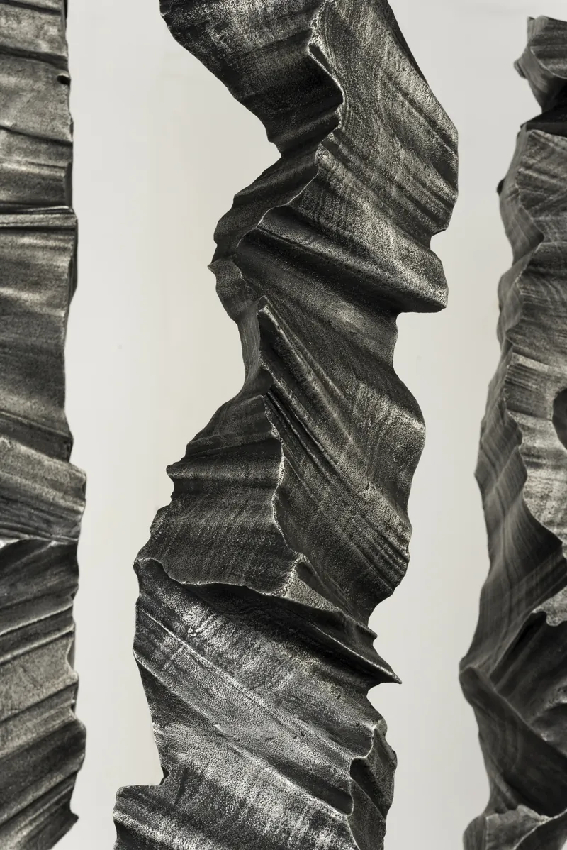Close view of folded aluminium surfaces, with neighbouring columns at the frame edges