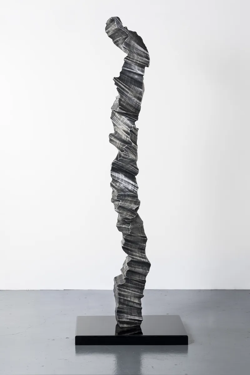 A single aluminium column on a black plinth, full view