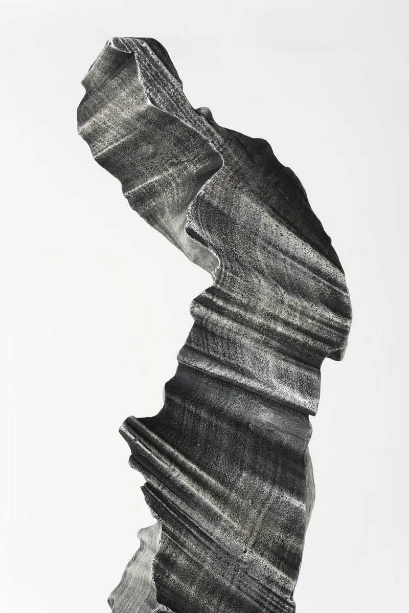 The twisting upper section of a column against a white wall